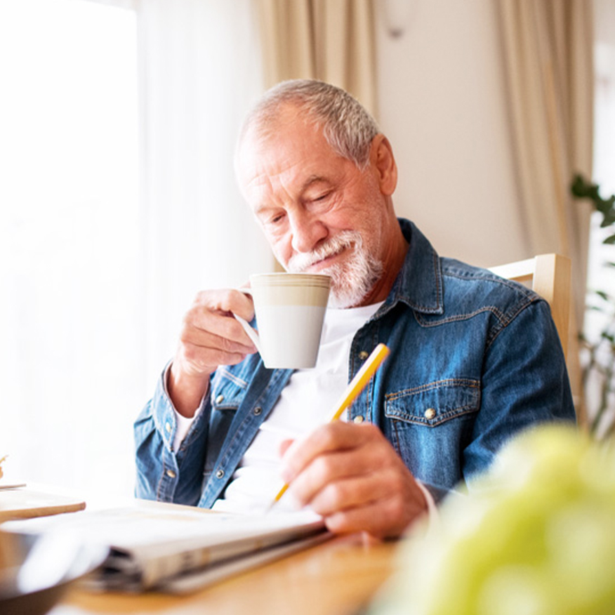 Ευκρινέστερη λειτουργία του εγκεφάλου - Μεσήλικας που εργάζεται σε ένα παζλ εφημερίδων πίνοντας ένα φλιτζάνι τσάι